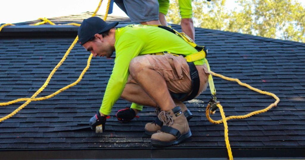 a man on a roof on a residential roof replacement process
