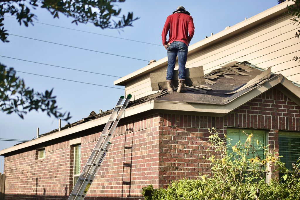 a man on a roof with red shirt on a residential roof replacement process